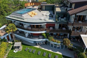 A multi-story residential building with a rooftop pool, outdoor seating areas, and a well-maintained garden. - MARINIs giardino Hotel (Tirolo)