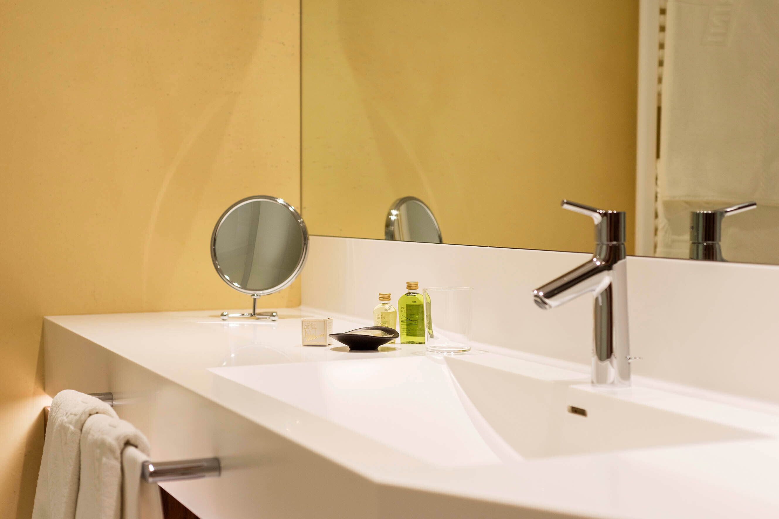 A modern bathroom with a white sink, a mirror, and a chrome faucet.