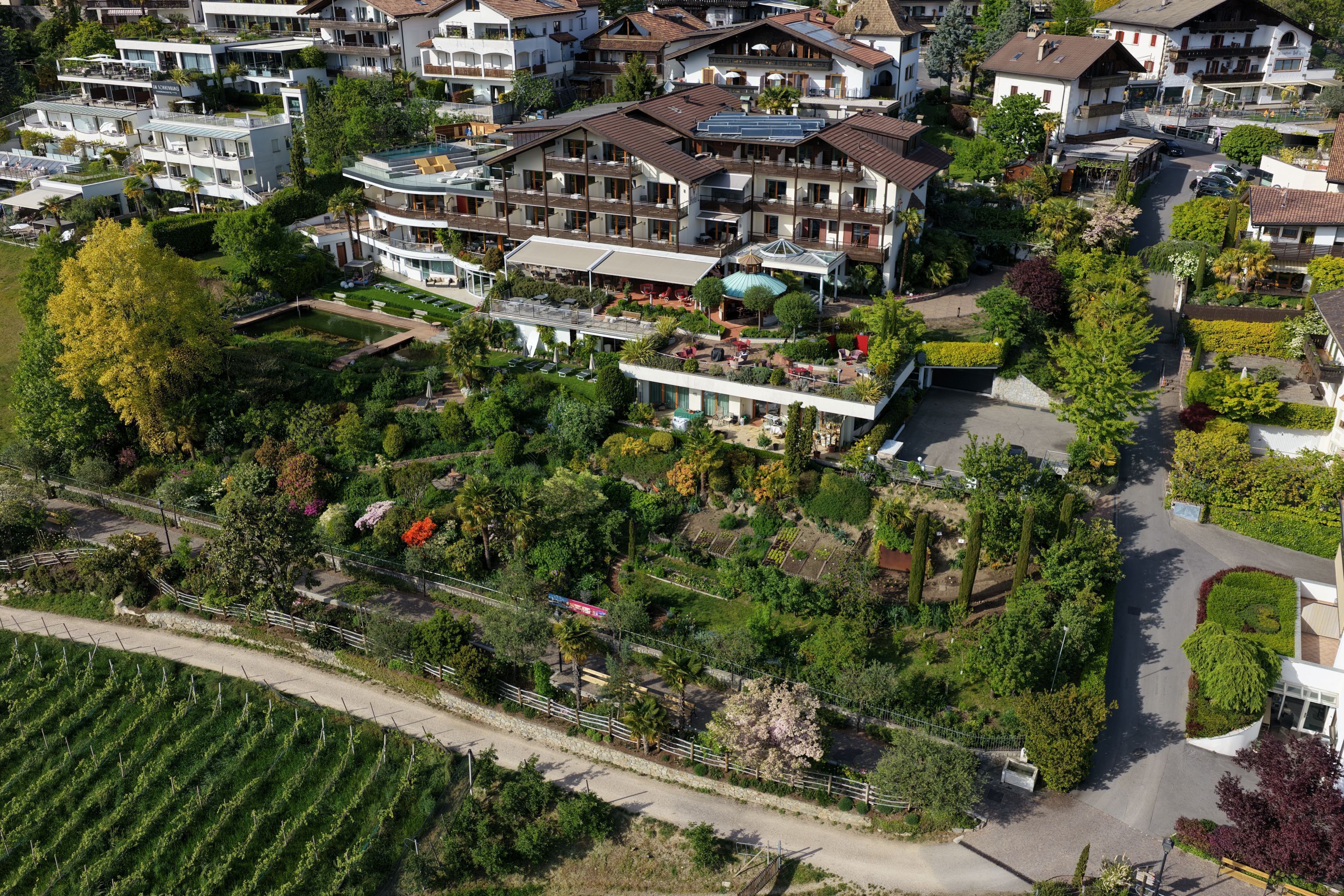 An aerial view of a residential area with multi-story buildings, gardens, and a road.