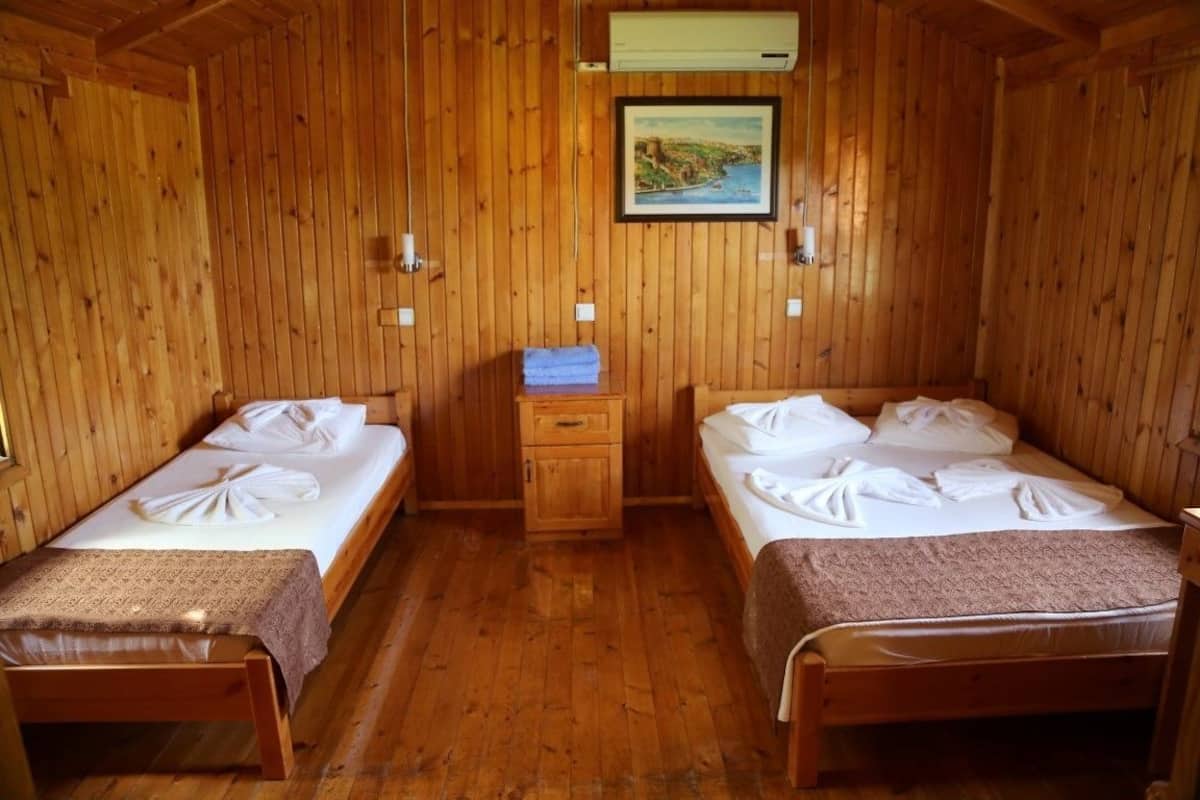 A room with two wooden beds, a small wooden cabinet, and a framed picture on the wall.