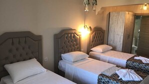Ein Hotelzimmer mit zwei Einzelbetten, einem großen Fenster und einem Holzschrank.