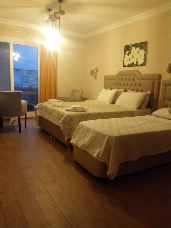 Habitación de hotel con dos camas, una silla, una mesa y una ventana con cortinas.