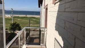 Ein Balkon mit Blick auf das Meer und ein weißes Backsteingebäude.