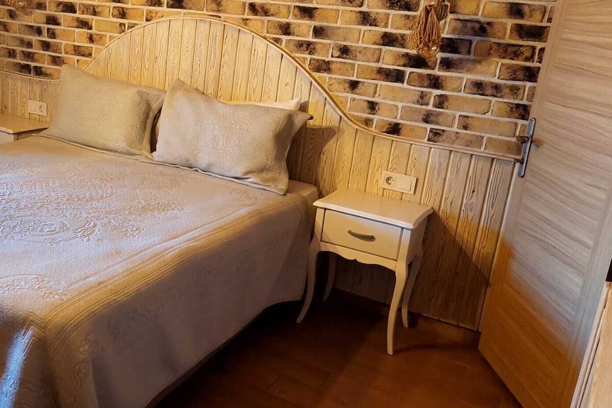 A bed with a patterned bedspread, two bedside tables, and a brick-patterned headboard.