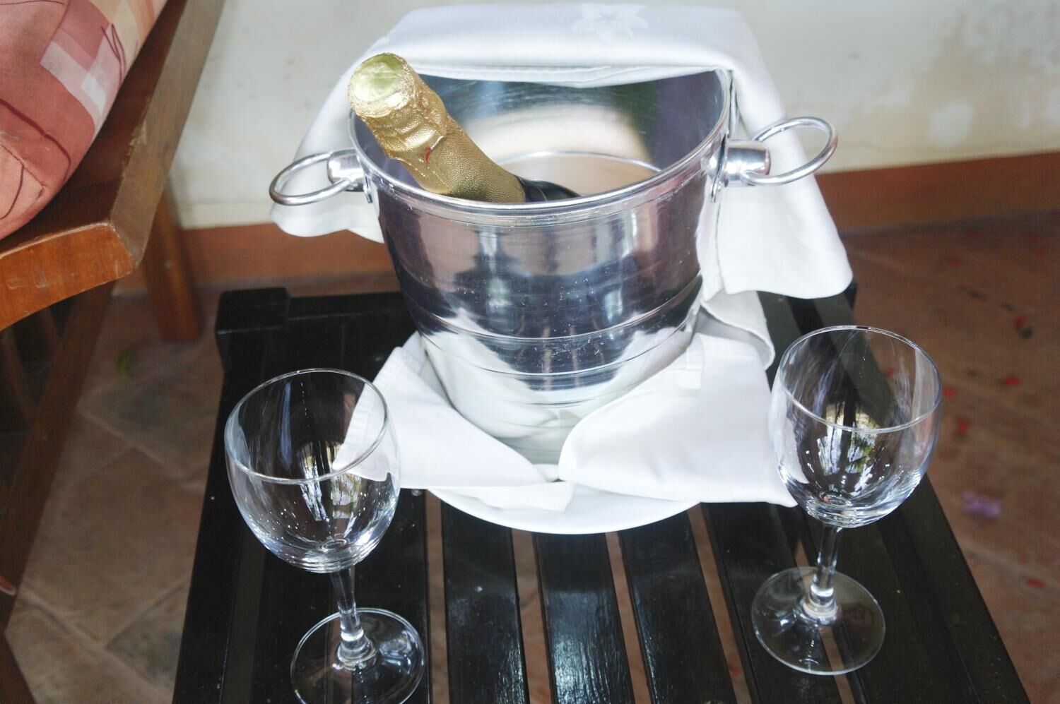 Un récipient métallique contenant un objet doré, placé sur une table noire, avec deux verres vides à côté.