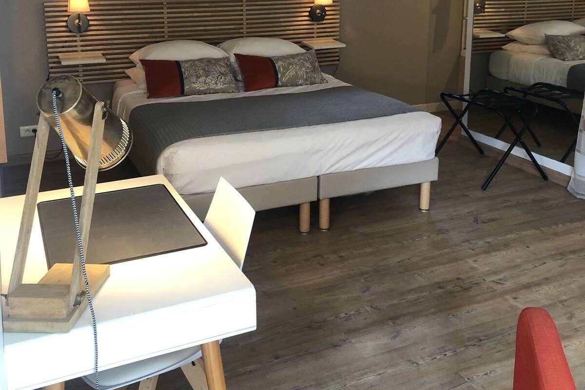 Une chambre d’hôtel comprenant un lit, des lampes de chevet, un bureau avec une lampe et une chaise.