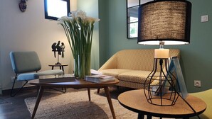 A living room with a sofa, a chair, a coffee table, a lamp, and a decorative deer head.