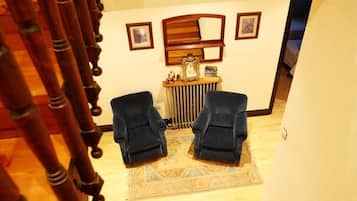 A staircase leading to a room with two chairs, a radiator, and framed pictures on the wall.