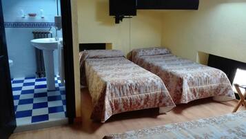 Una habitación con dos camas, un lavabo y un suelo a cuadros.