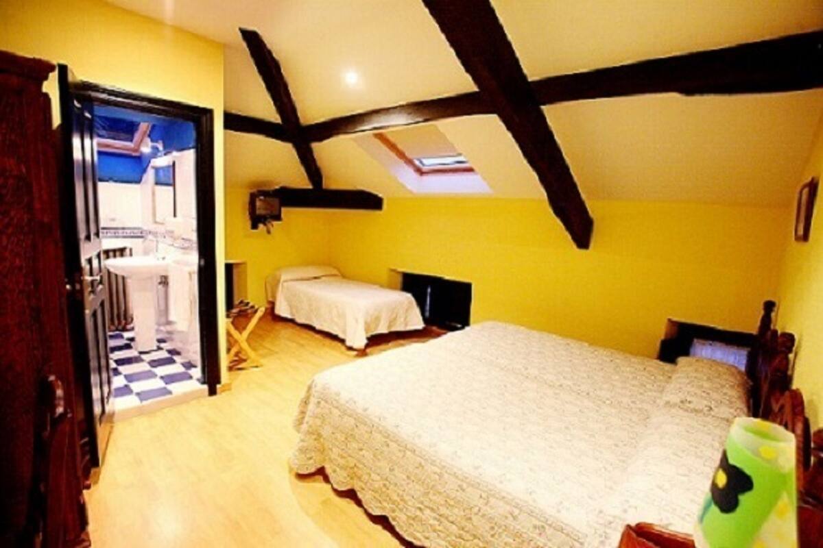 A bedroom with a large bed, a smaller bed, a desk, and a chair. There is a window with a view of the outside.