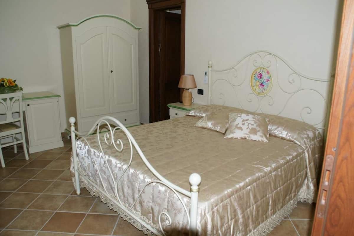 A bedroom with a bed, a desk, and a wardrobe.