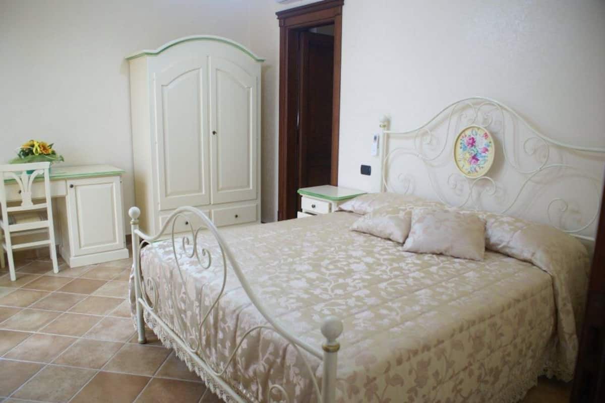 A bedroom with a bed, a dresser, a wardrobe, and a desk.