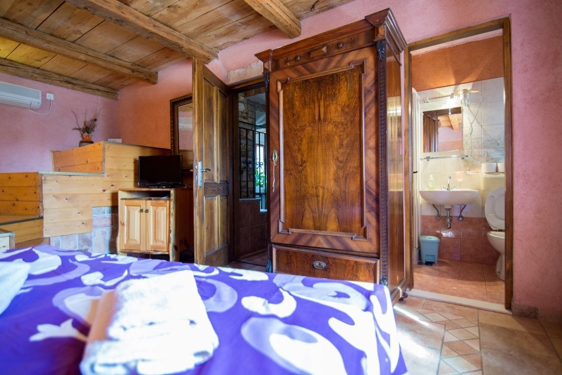 A room with a bed, wooden cabinets, a television, and a bathroom visible through an open door.