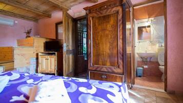 A room with a bed, wooden cabinets, a television, and a bathroom visible through an open door.