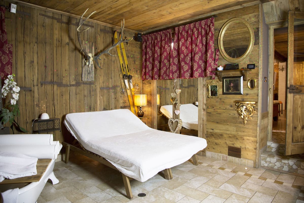 Une pièce rustique en bois, avec un lit, un miroir et un crâne de cerf accroché au mur.