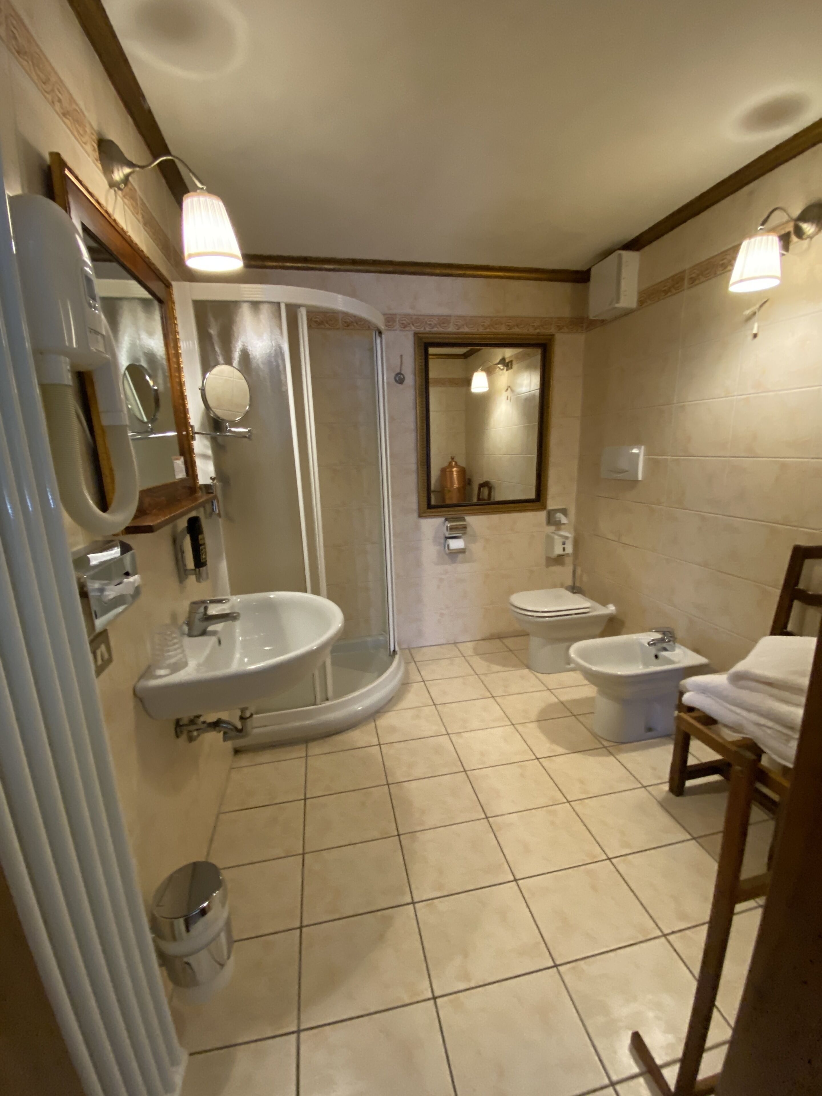A bathroom with a shower, two sinks, a toilet, and a bidet.