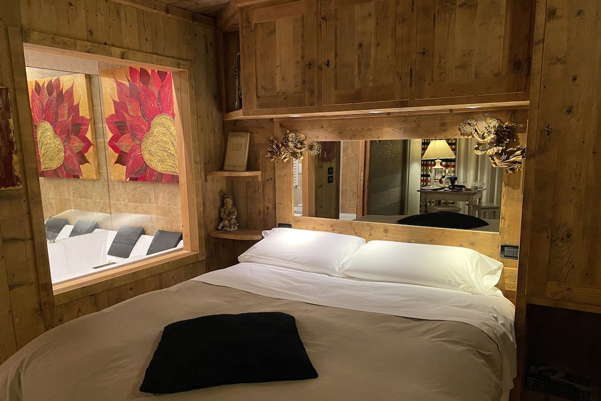 Une pièce en bois avec un lit, une fenêtre et un miroir.