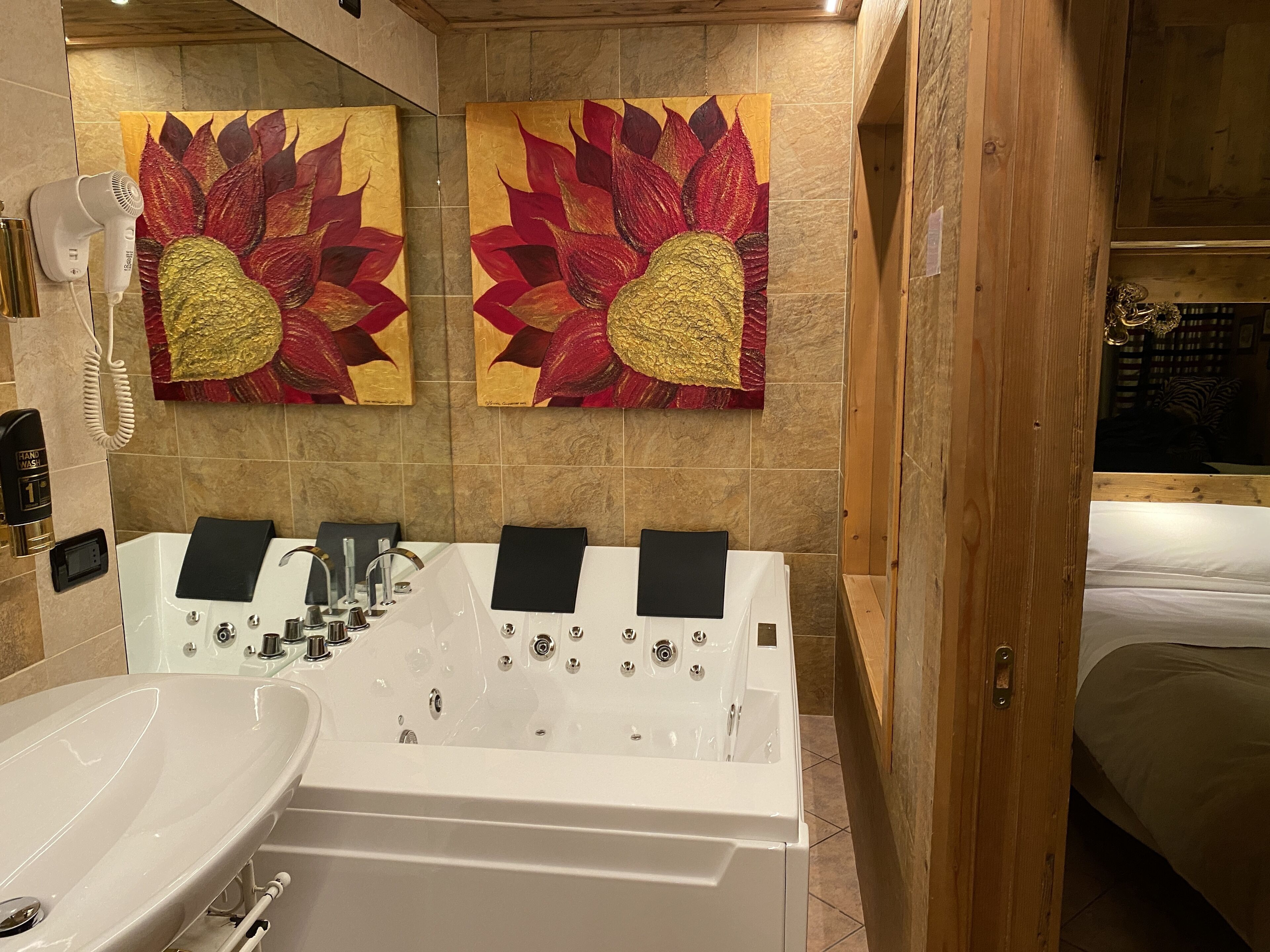 A modern bathroom with a large bathtub, a sink, and two wall-mounted hair dryers.