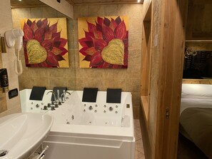 A modern bathroom with a large bathtub, a sink, and two wall-mounted hair dryers.