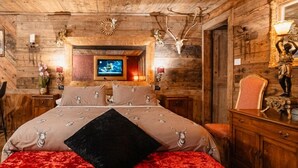 Een rustieke houten kamer met een bed, een televisie en een spiegel met een beeldje.