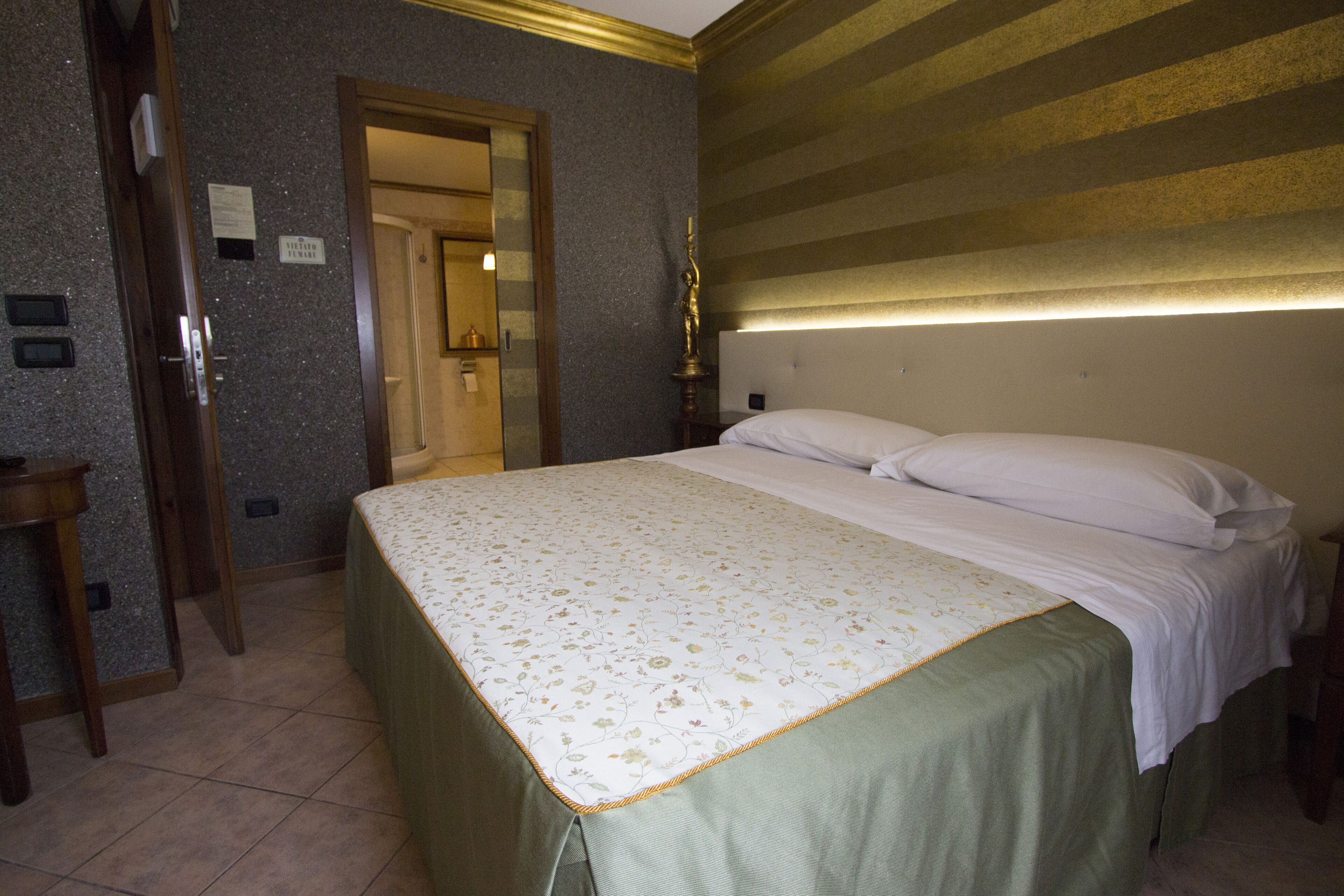 Ein Hotelzimmer mit einem Bett, einem Nachttisch, einem Spiegel und einer Tür zu einem Badezimmer.