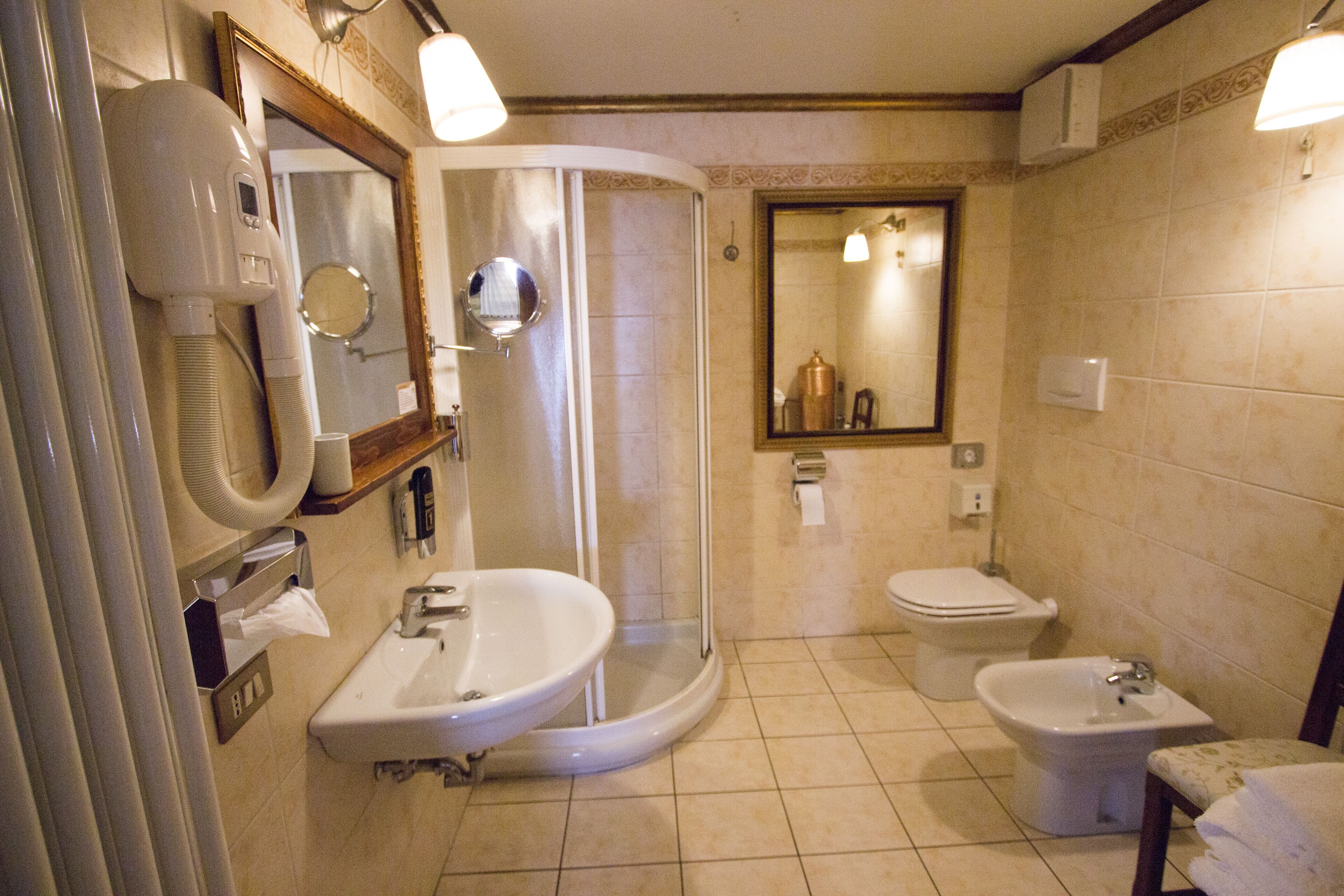 Un baño con ducha, dos lavamanos, inodoro y bidé.