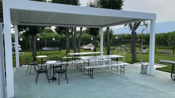 Un'area patio all'aperto con tavoli e sedie, un'amaca e una zona salotto coperta.