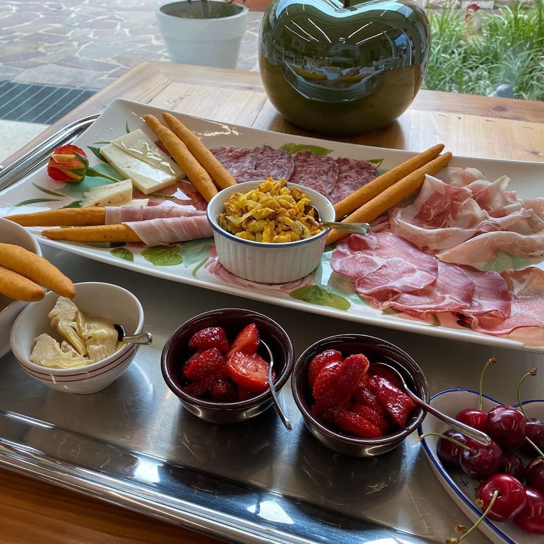 Una tabla de embutidos con diversos quesos y frutas.