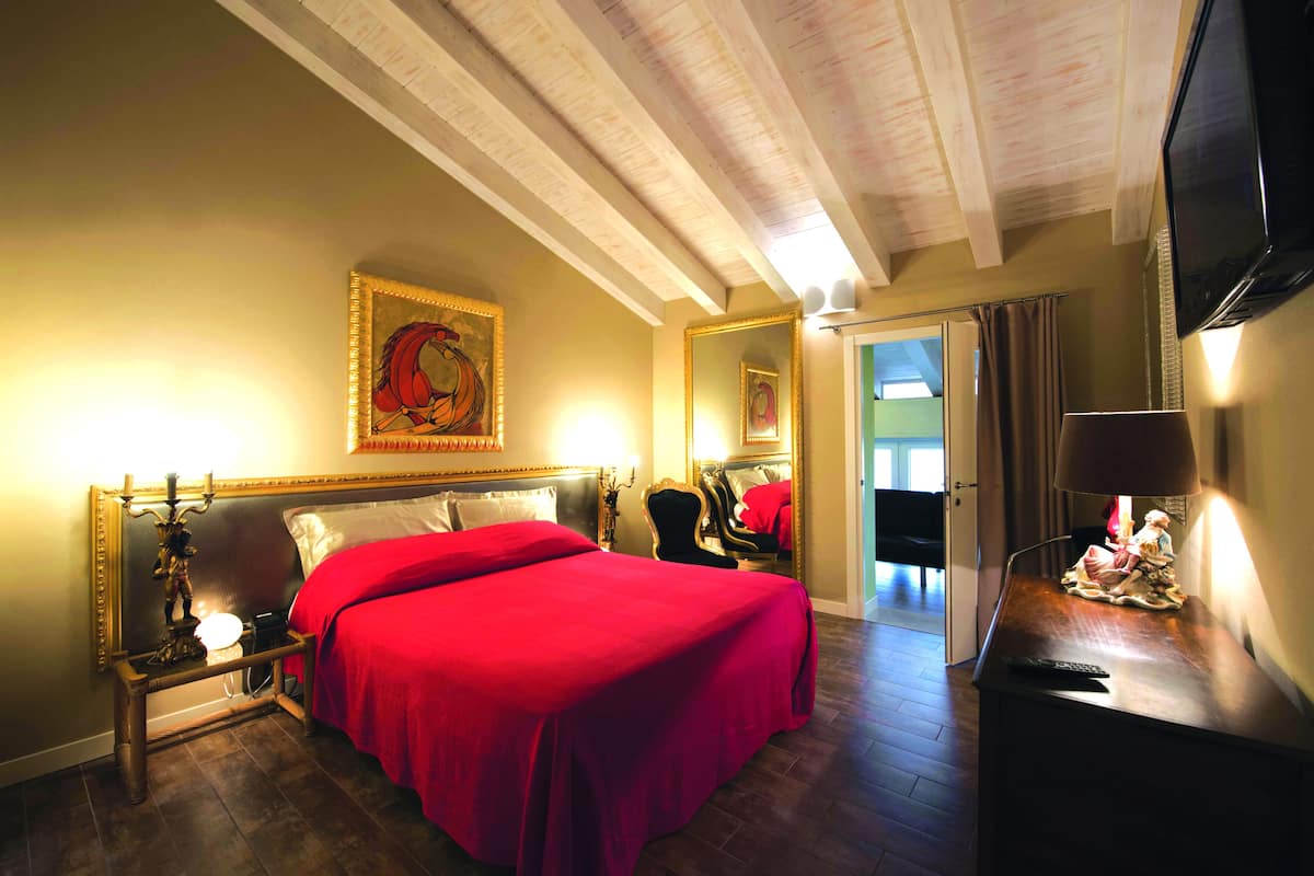 Une chambre d’hôtel avec un grand lit, une table de chevet avec une lampe, un miroir et un téléviseur.