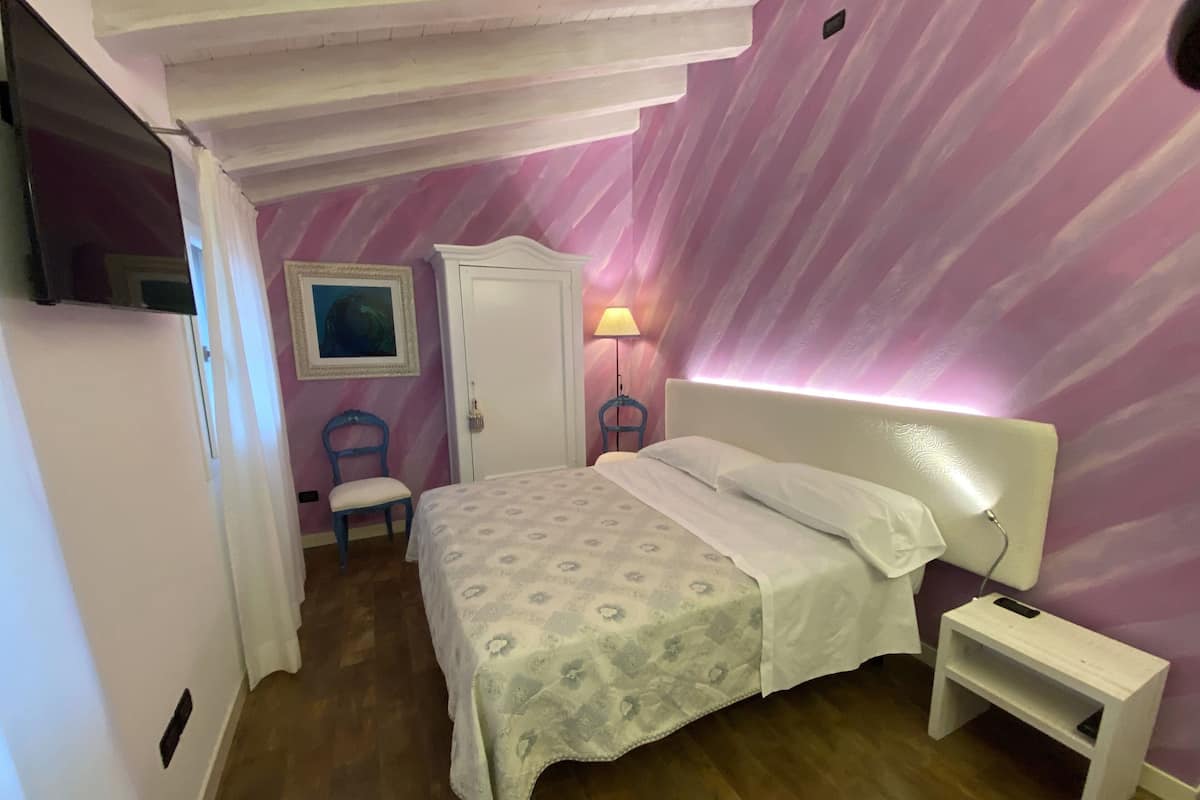Une chambre à coucher avec un lit, une table de chevet, une chaise, une armoire et un tableau au mur.