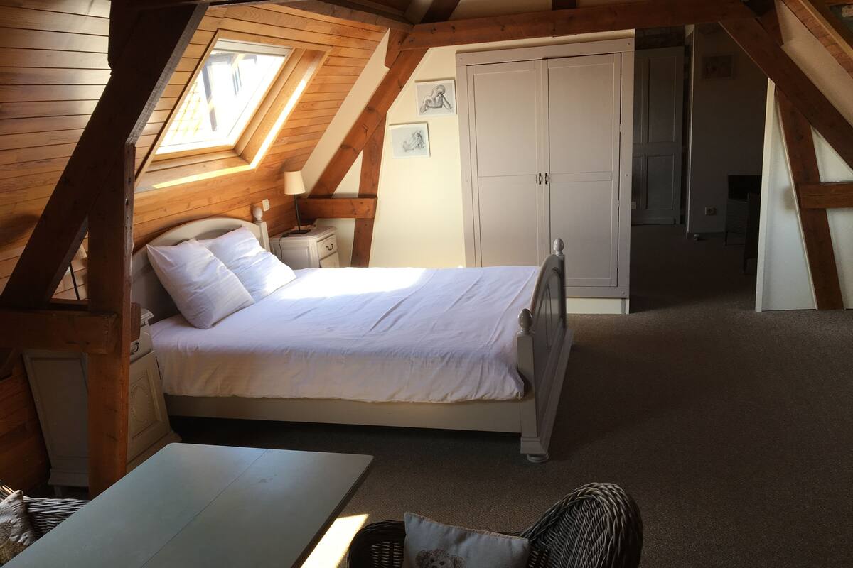 Quarto com cama, mesa de cabeceira, abajur, guarda-roupa e janela.