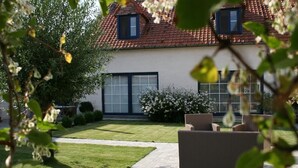 A house with a tiled roof, a well-maintained lawn, and outdoor furniture. - B&B 't Wolvennest (Heuvelland)