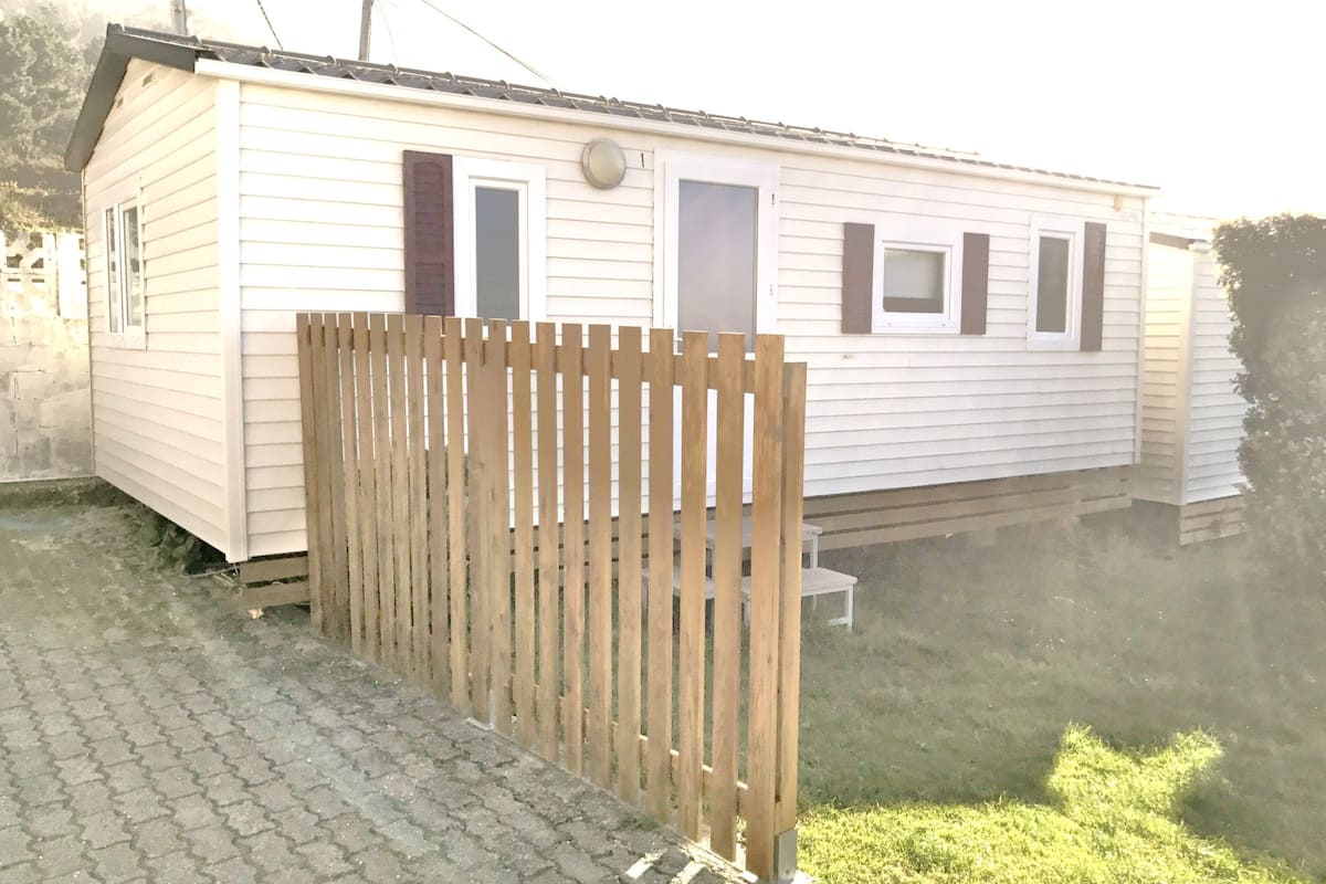 A single-story mobile home with a wooden fence in front.