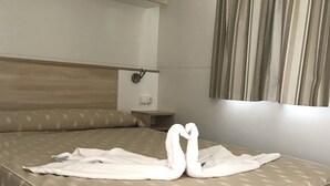 Een keurig opgemaakt bed met een beddekleed met dessin en twee handdoeken gevouwen in de vorm van zwanen.