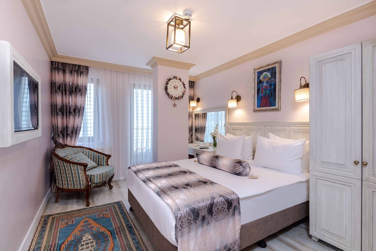 Un dormitorio con una cama grande, una silla, una alfombra, un reloj y un armario.