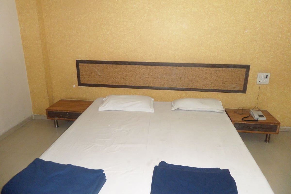 A standard hotel room with a large bed, two bedside tables, and a wall-mounted telephone.