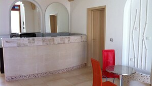 A kitchen with a marble countertop, a sink, and a red chair. - Affittacamere Torre Lapillo (Porto Cesareo)