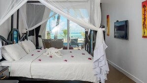 A bedroom with a bed, white curtains, a view of the ocean, and a chair. - Sofia Sea View (Pwani Mchangani)