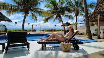 Een buitenzwembad, parasols bij het zwembad en ligstoelen