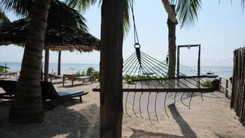 Una playa con una hamaca, palmeras y sillas de descanso.