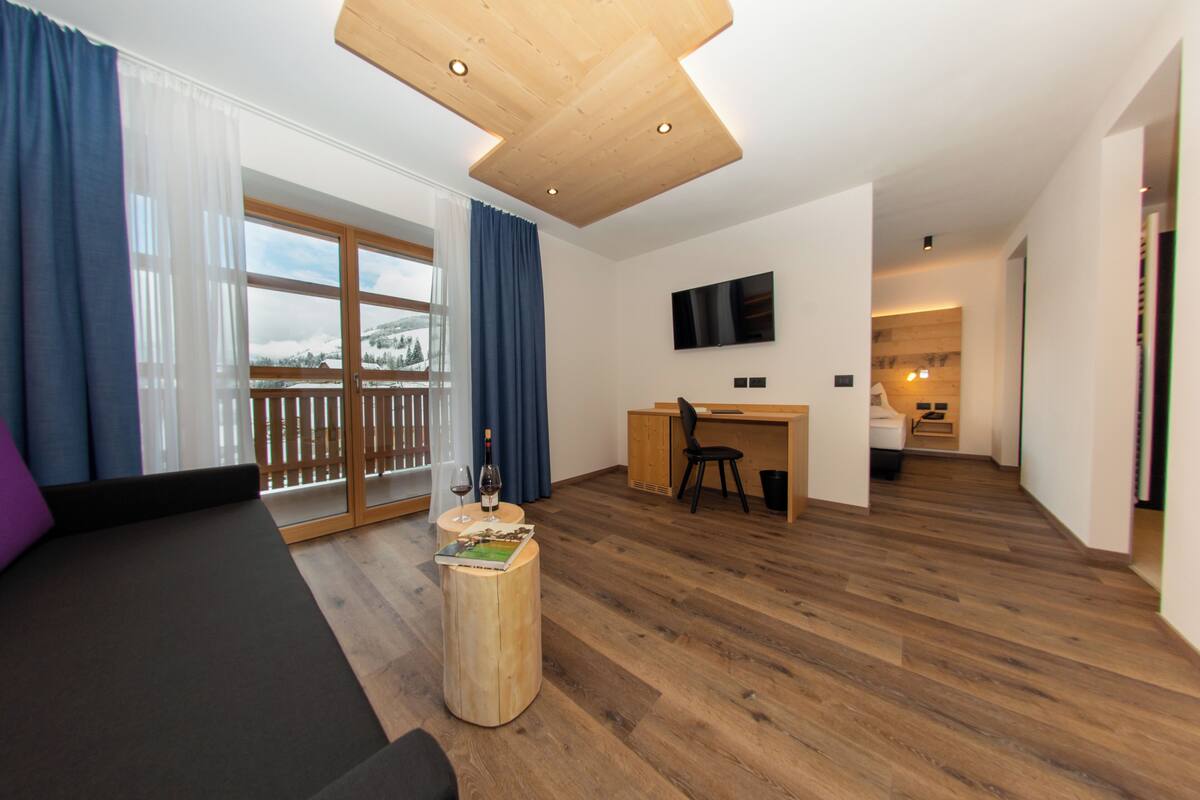 Una sala de estar moderna con un sofá, una mesa de centro de madera y vistas a un paisaje nevado a través de amplios ventanales.