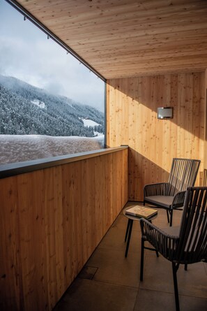 A wooden-paneled room with a view of snow-covered mountains, a table with chairs, and a small wall-mounted light. - Hotel Gran Pre (Marebbe)