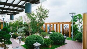 A serene garden with a wooden deck, stone lanterns, and a pergola structure. - Park Hill No1 Apartment (Hanoi)