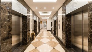 A modern hallway with marble walls and a checkered floor, leading to elevators. - Park Hill No1 Apartment (Hanoi)