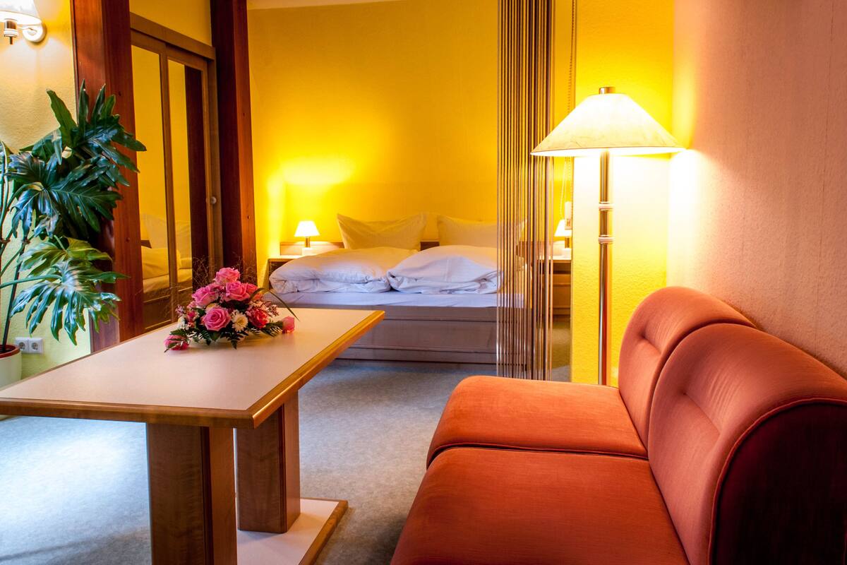 Ein Hotelzimmer mit einem Bett, einer Couch, einem Tisch mit Blumenarrangement und einer Lampe.