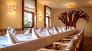 Une longue table à manger, recouverte de nappes blanches, agrémentée de serviettes et de verres, et entourée de chaises en bois.