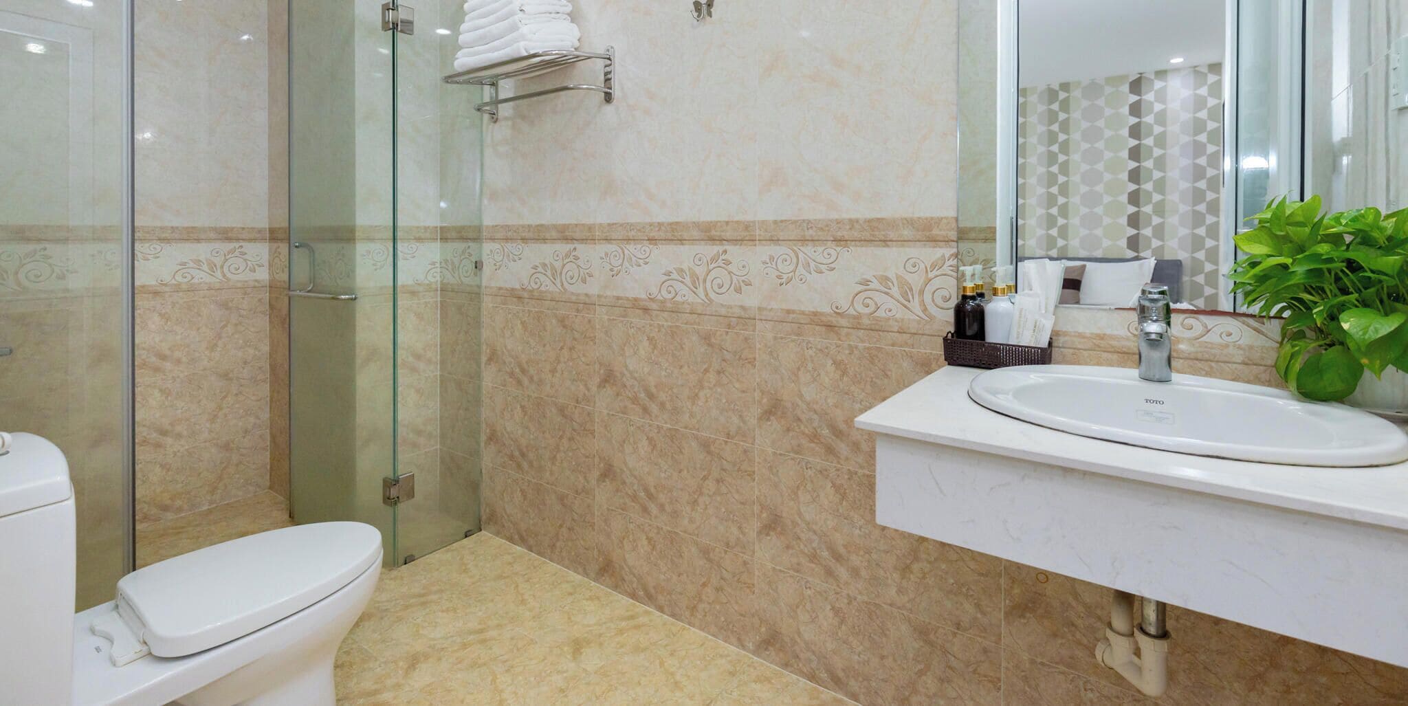 A modern bathroom with a glass-enclosed shower, a white toilet, and a sink with a mirror above it.