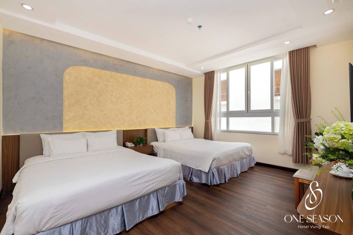 Ein Hotelzimmer mit zwei Betten, einem großen Fenster, Holzboden und einer wandmontierten Kopfteil.
