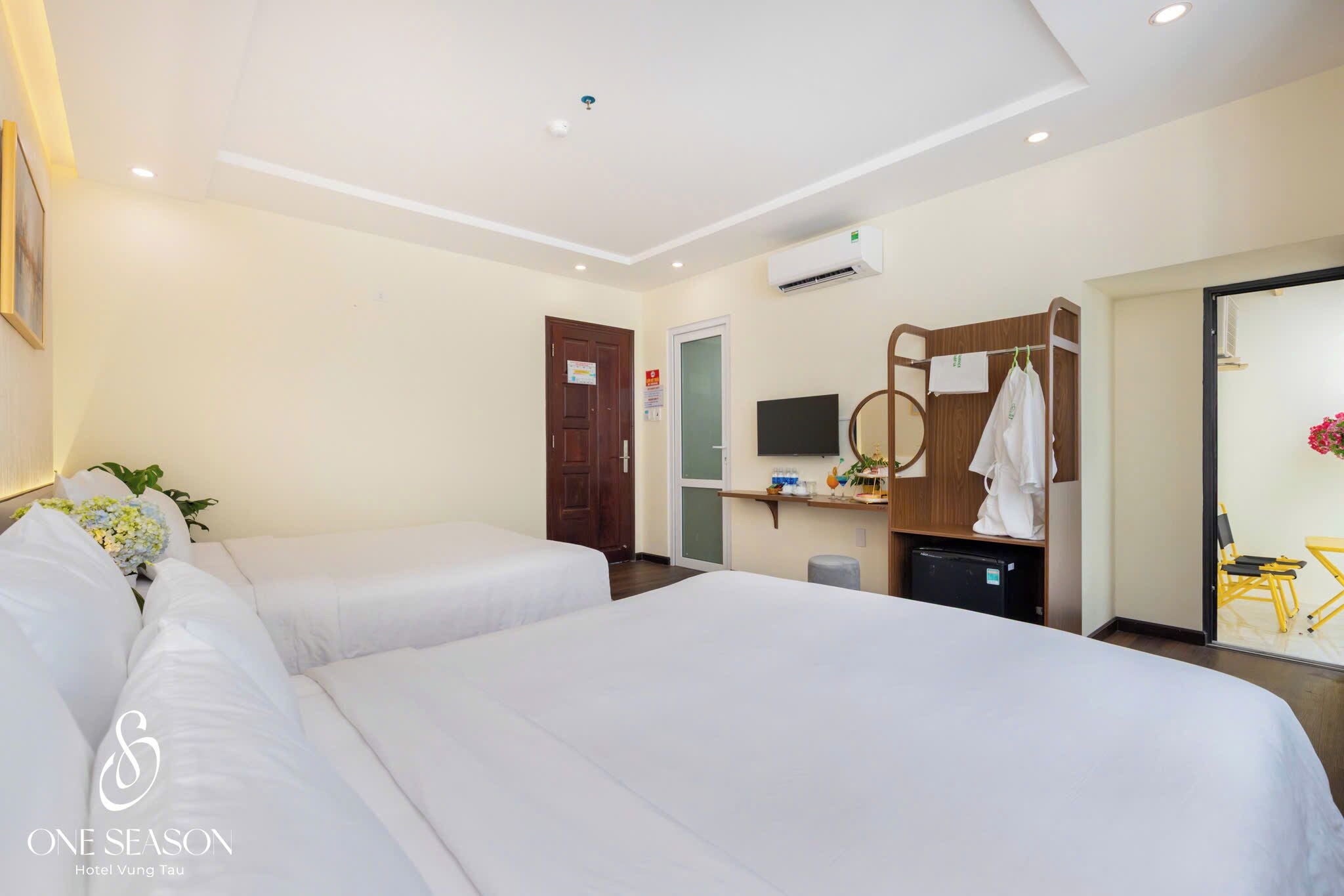 A hotel room with two beds, a TV, a desk with a chair, and a bathroom visible through an open door.
