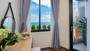 A room with a large window, a wooden desk, a mirror, and a potted plant. -  One Season Boutique Hotel Vung Tau - Beachfront (Ho Chi Minh City)